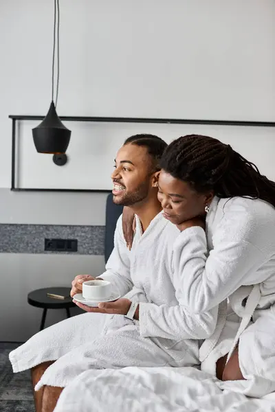 Ein junges Paar entspannt sich in einem Hotelzimmer und teilt Lachen und Freude bei einem Kaffee während ihres Urlaubs. — Stockfoto