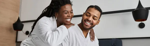 Um alegre casal afro-americano abraça enquanto desfruta de umas férias juntos em um elegante quarto de hotel. — Fotografia de Stock