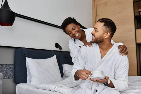 A young African American couple shares a joyful moment together in their hotel room, radiating love and happiness. — Stock Photo