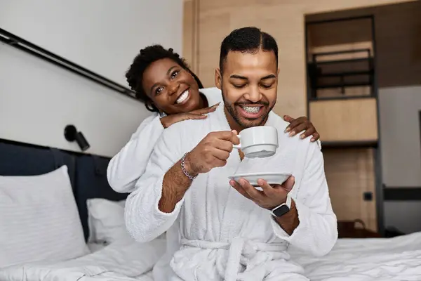 A young couple shares joyful moments in their hotel room, savoring coffee and each others company. — Stock Photo