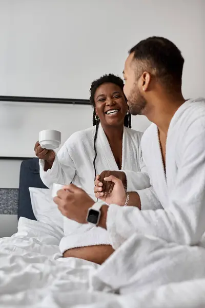 Um jovem casal alegre compartilhar uma xícara de café, abraçando o amor e relaxamento em seu retiro do hotel. — Fotografia de Stock