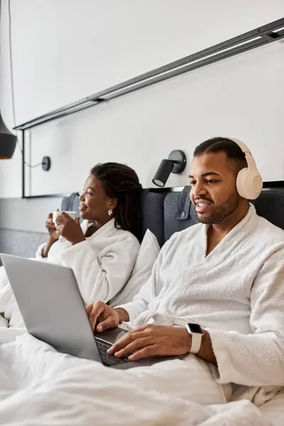 A young couple relaxes in a hotel room, enjoying their vacation while connected and cozy together. — Stock Photo