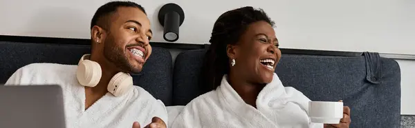 A young couple enjoys laughter and connection in their cozy hotel room while relaxing together. — Stock Photo
