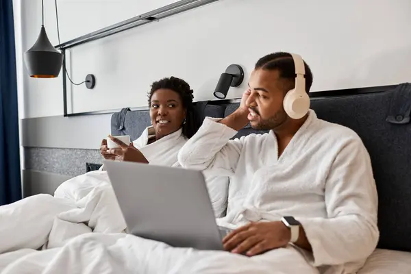 Ein junges Paar entspannt sich in einem Hotelzimmer und genießt Lachen und ein warmes Getränk während seines Urlaubs. — Stockfoto