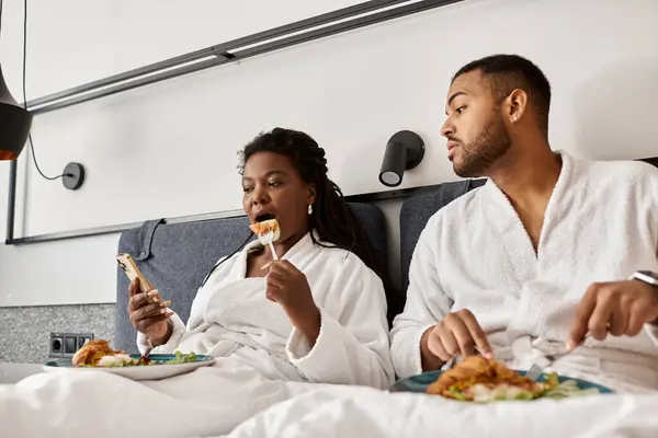 A young couple relaxes in their hotel room while enjoying breakfast and each others company during vacation. — Stock Photo