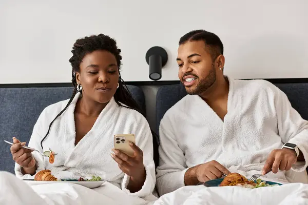 A young couple shares laughter and a meal in their hotel room while enjoying their vacation. — Stock Photo