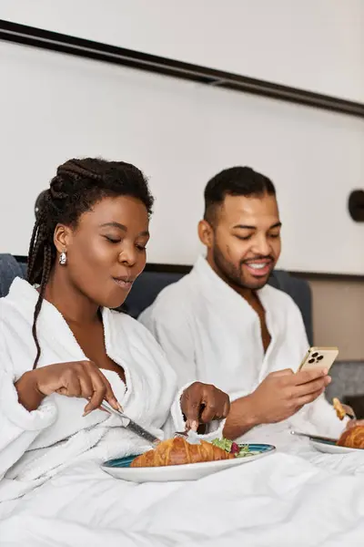 A delighted couple savoring breakfast together, sharing moments of love in a relaxing hotel setting. — Stock Photo