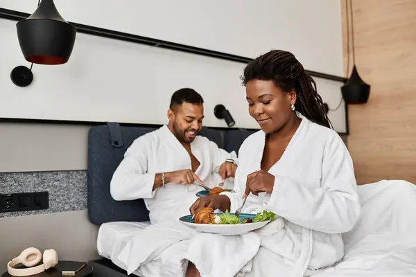 Una coppia condivide una deliziosa colazione insieme in una elegante camera d'albergo, celebrando il loro amore e vacanza. — Foto stock