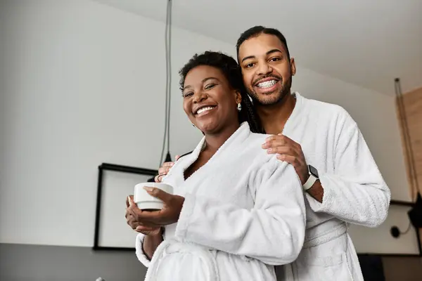 A joyful young couple embraces in a cozy hotel room, savoring their vacation together with laughter and warmth. — Stock Photo