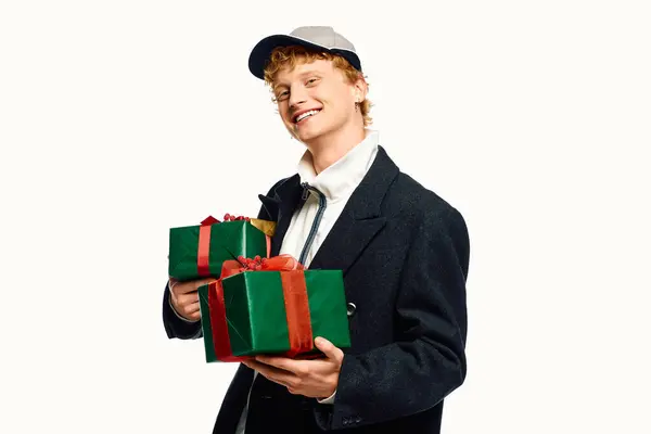 Against a clean backdrop, a joyful man presents two beautifully wrapped green gifts adorned with vibrant ribbons. — Stock Photo