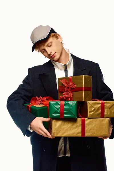 Dressed in festive fashion, a man joyfully carries a stack of beautifully wrapped Christmas presents. — Stock Photo