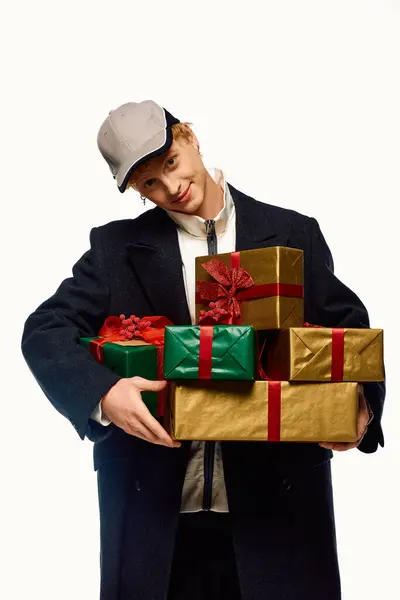Celebrating the joy of Christmas in 2025, a fashionable man showcases his holiday spirit while carrying beautifully wrapped presents. — Stock Photo