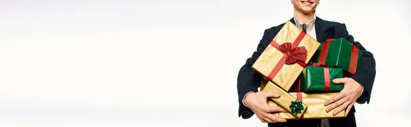 A well dressed man joyfully holds an assortment of beautifully wrapped gifts adorned with festive ribbons. — Stock Photo