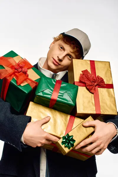 A stylish young man showcases contemporary holiday fashion while holding an array of beautifully wrapped gifts. — Stock Photo