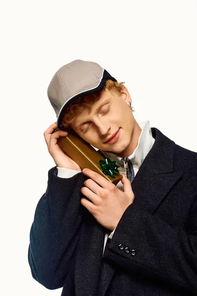 A stylish man in festive attire enjoys a joyful moment while holding a beautifully wrapped Christmas gift. The ambiance radiates holiday cheer as he anticipates the joys of giving and receiving. — Stock Photo