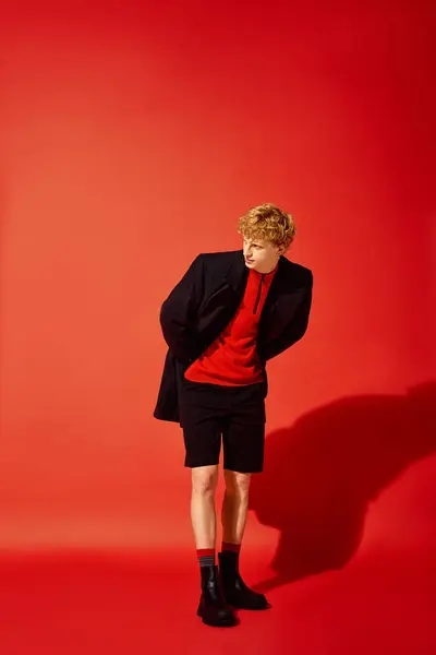 Um homem elegante está confiante em uma roupa ousada com uma camisola vermelha e shorts, emparelhado com um blazer preto. — Fotografia de Stock