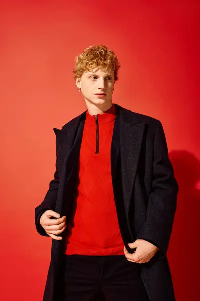 A fashionable man poses confidently against a vibrant red background, showcasing a chic ensemble perfect for the holiday season. — Stock Photo