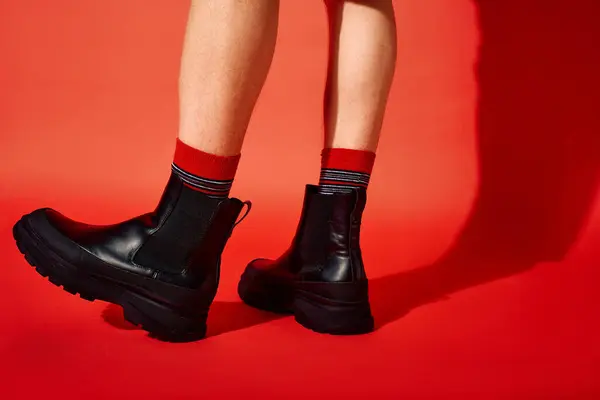 A man models trendy black boots paired with festive red socks, making a fashion statement perfect for holiday celebrations. — Stock Photo