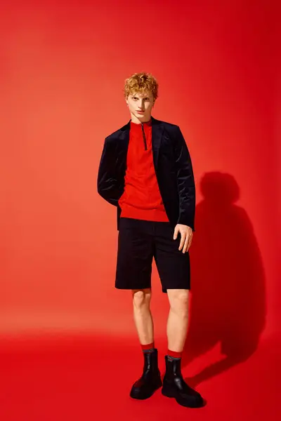 A fashionable man stands confidently in a striking red sweater and black shorts, complemented by stylish boots. The festive atmosphere captures the spirit of Christmas 2025, radiating holiday cheer. — Stock Photo