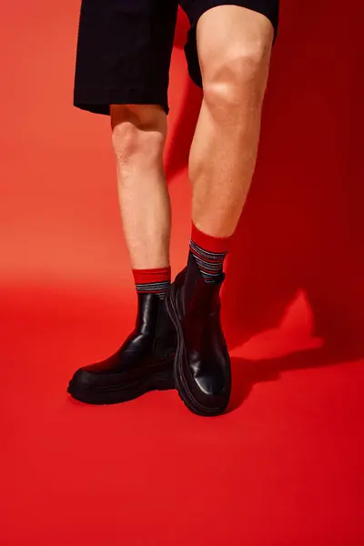 Um homem modela a moda festiva de férias com botas pretas elegantes emparelhadas com meias vibrantes vermelhas e listradas. — Fotografia de Stock