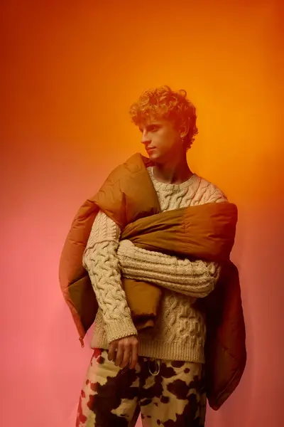 A man showcases a trendy holiday outfit featuring a cozy sweater and a warm outer layer, exuding modern charm with playful patterns. Bold colors enhance the festive spirit,. — Stock Photo