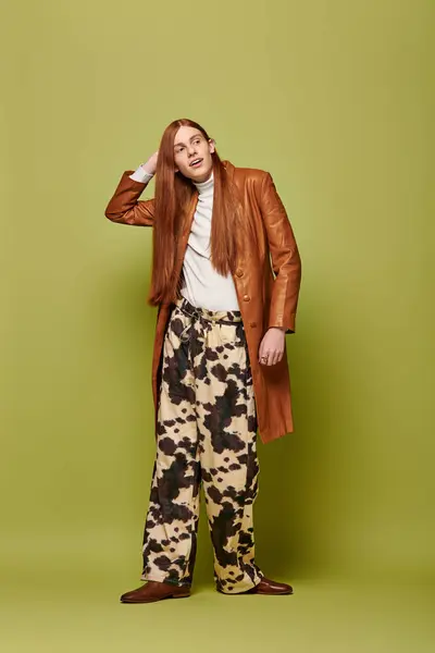 Young man in stylish outfit expresses deep emotions with long flowing red hair in bright setting. — Stock Photo