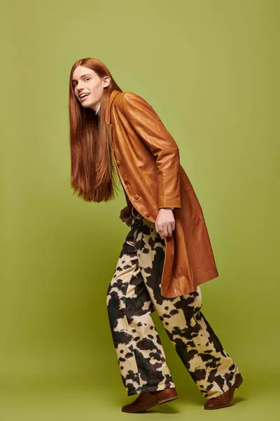 A young man with long red hair showcases a playful joy, dressed in stylish attire. — Stock Photo