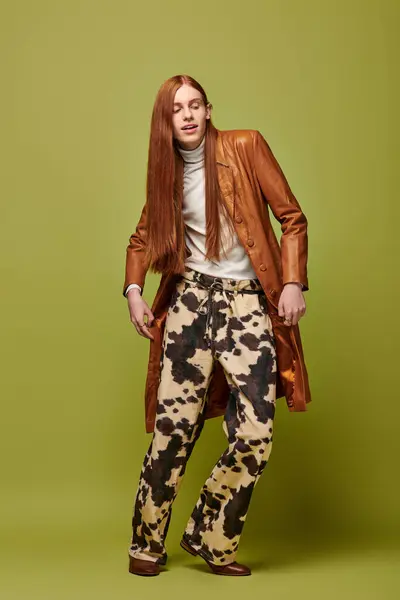 Young man with long red hair in unique clothes, radiating emotion against a vibrant backdrop. — Stock Photo