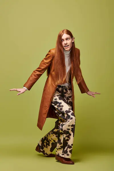 Joven emocionalmente expresivo muestra sentido de la moda con pelo largo rojo y pantalones estampados. — Stock Photo