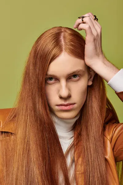 Young man with long red hair expresses deep emotions in stylish attire and a vibrant setting. — Stock Photo