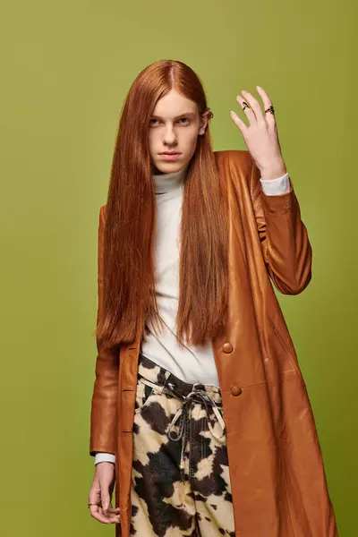 A young man with long red hair showcases his emotions against a vibrant green background. — Stock Photo