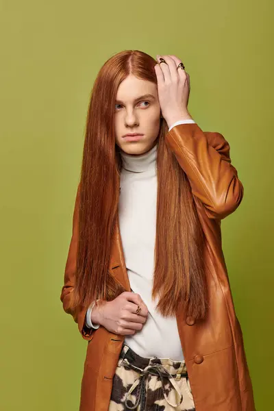 Un jeune homme aux longs cheveux roux montre des émotions profondes dans un manteau marron élégant. — Photo de stock