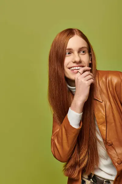 A young emotional man with long red hair smiles while playfully posing for a striking photo. — Stock Photo