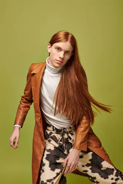 Confident young man with long red hair poses in a trendy outfit and vibrant setting. — Stock Photo