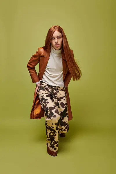 Emotional young man with long red hair poses dramatically against a bright green background — Stock Photo