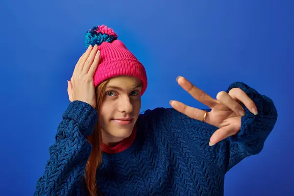 Young man with long red hair poses playfully in a colorful beanie, showing vibrant emotions. — Stock Photo