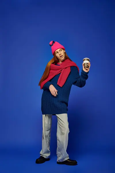 Emotional young man with long red hair stands confidently against a bright blue background. — Stock Photo