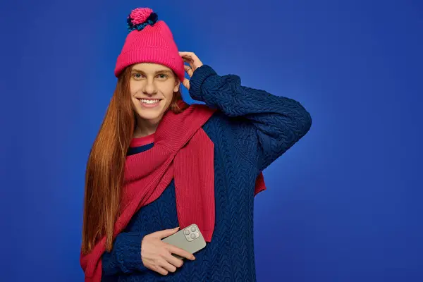 Excited young man with long red hair poses in vibrant winter fashion, full of joy. — Stock Photo