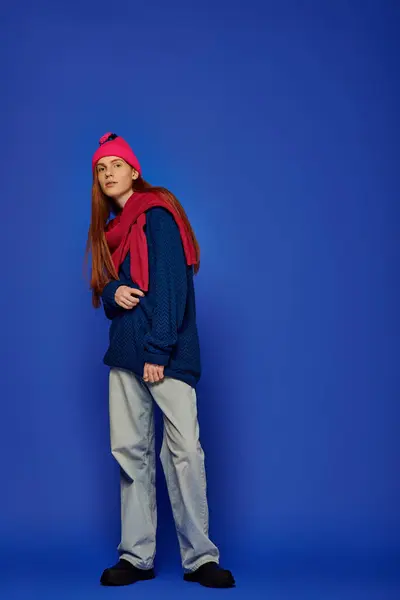 Un giovane con lunghi capelli rossi mostra emozioni profonde mentre si veste con disinvoltura in un maglione blu. — Foto stock