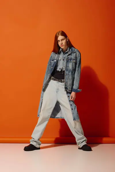 Young man with long red hair showcases emotions while dressed in stylish denim attire. — Stock Photo