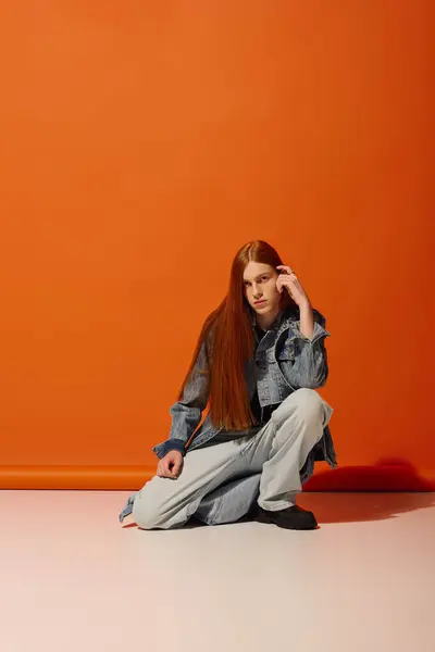 Emotional young man with long red hair poses gracefully in a unique setting, showcasing style. — Stock Photo