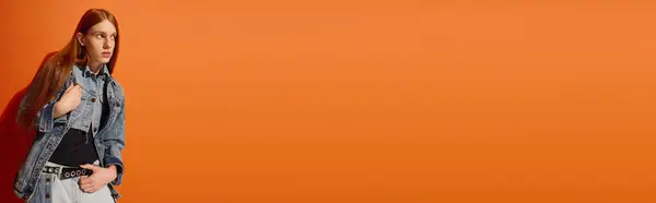A young man with long red hair poses emotionally against a vibrant orange backdrop. — Stock Photo