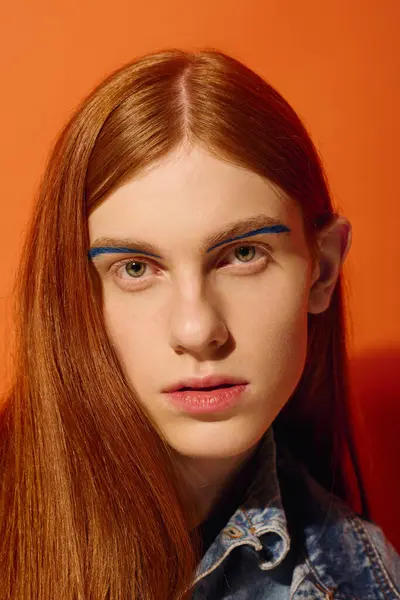 A young man with red hair and blue eyebrows evokes deep emotions in vibrant light. — Stock Photo