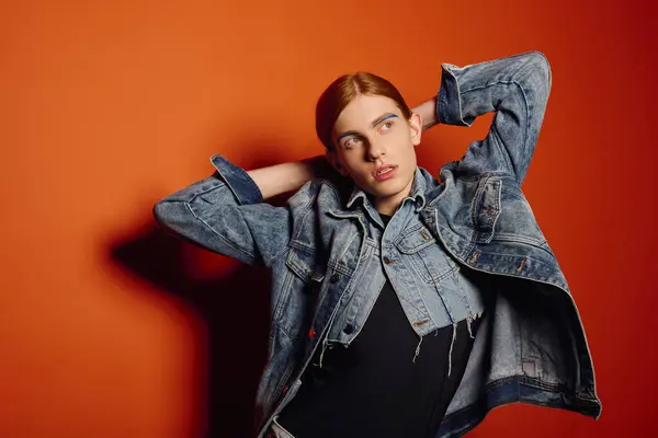 Emotional young man shows his feelings with long red hair against a bright orange wall — Stock Photo