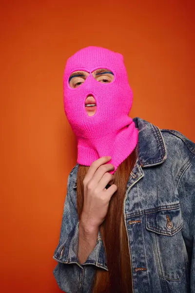 Young man with captivating red hair unveils his emotions while wearing a striking pink beanie. — Photo de stock