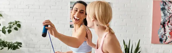 Two young women enjoy each others company as they bond during a playful workout session. — Stockfoto