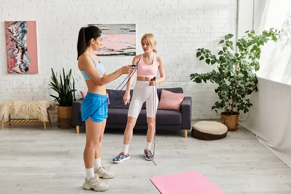 Two young women share a joyful moment while working out in a bright, inviting room. — Stock Photo