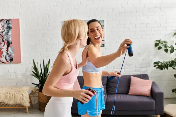 Two young women share laughter while exercising in their stylish home environment. — Stock Photo