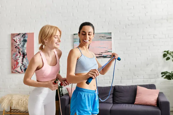 Two young women share laughter and joy while exercising with resistance bands at home. — Photo de stock