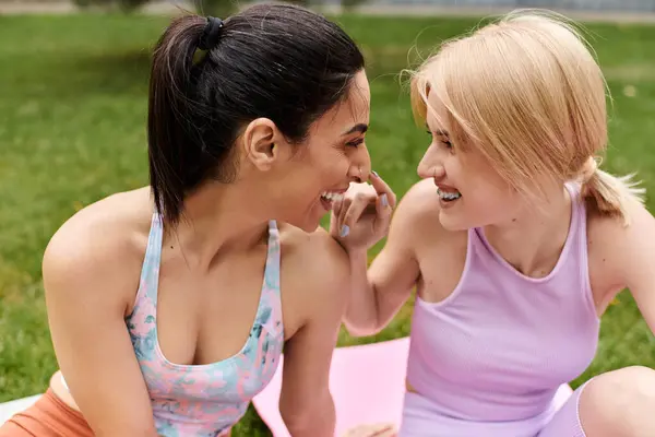 Two young women in vibrant outfits share a playful moment while enjoying nature together. — Stock Photo